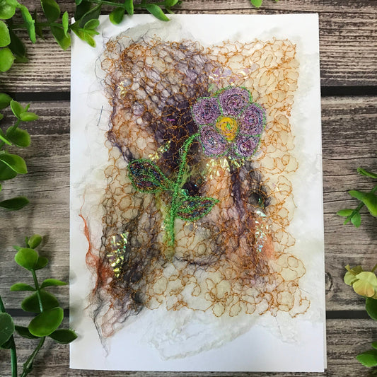 Carte de vœux avec une fleur de couleur mauve et jaune brodée sur la laine