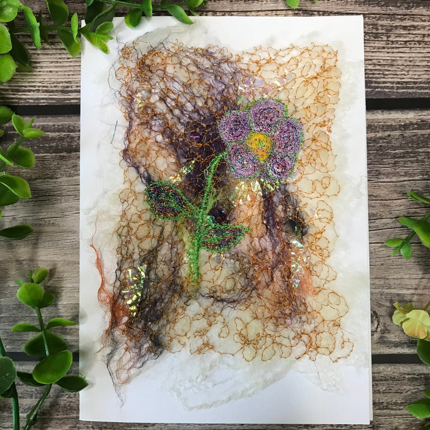Carte de vœux avec une fleur de couleur mauve et jaune brodée sur la laine