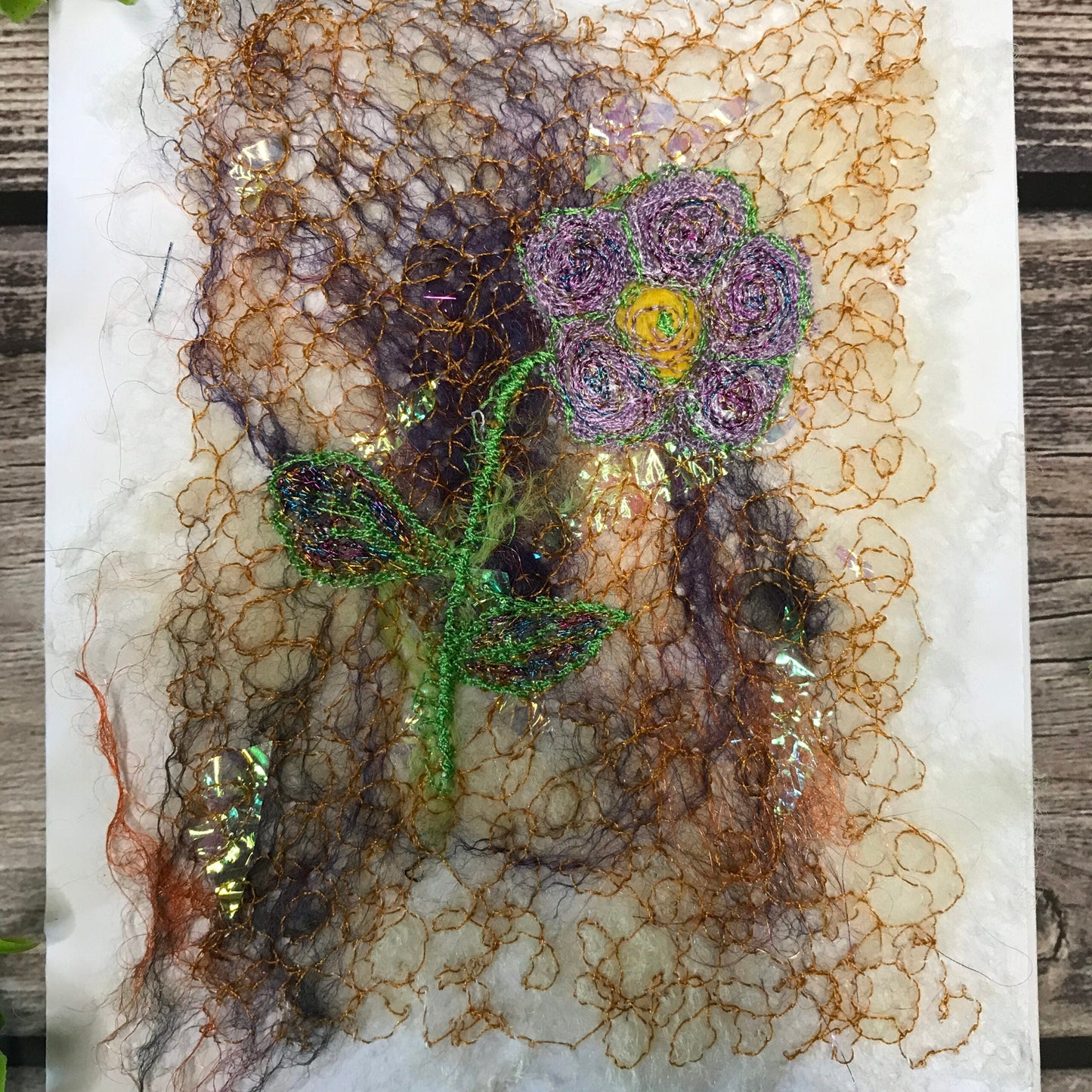 Carte de vœux avec une fleur de couleur mauve et jaune brodée sur la laine