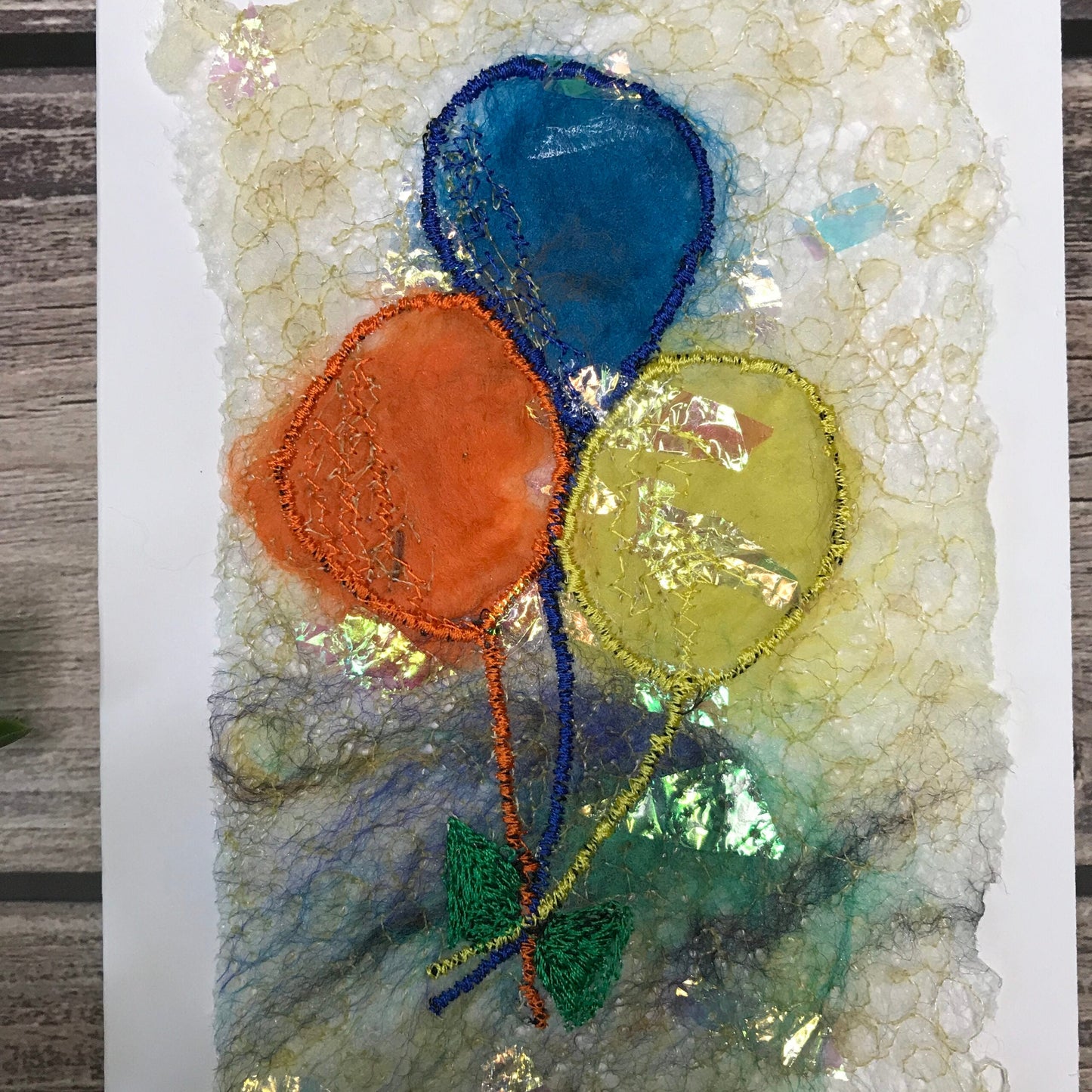 Carte de vœux avec jolis ballons oranges, bleus et jaunes brodée sur la laine