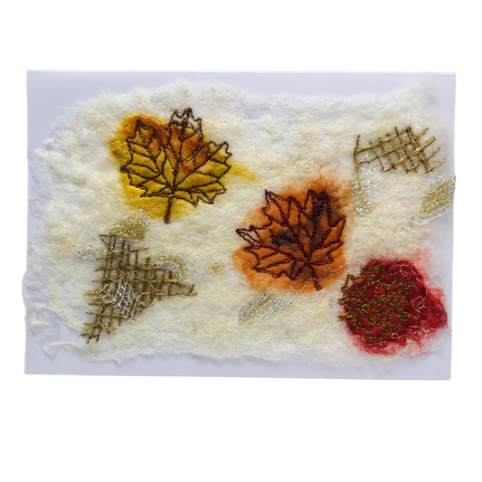 Carte de vœux avec trois feuilles d’érable jaune, orange et rouge brodée sur la laine